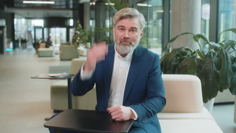 mature angry boss businessman shouting while looking at camera at modern workplace in office lobby