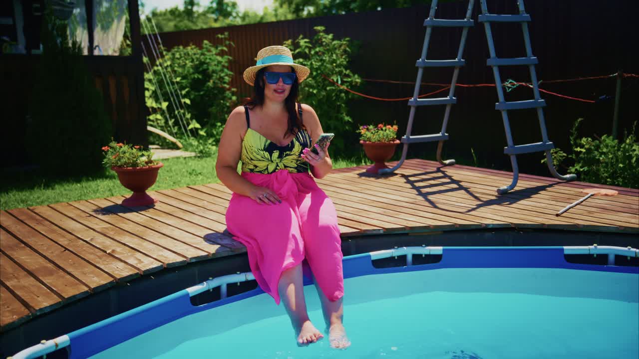 Woman in pink pants and hat relaxing by the poolside, enjoying summer leisure time outdoors