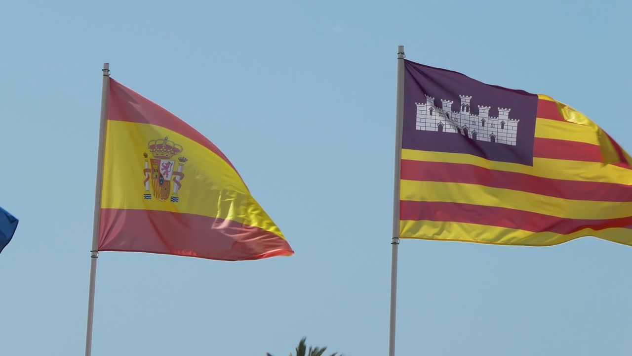 Ægte stof flag fra Spanien og Balearerne, et autonomt område i Spanien, vajende i vinden mod en blå himmel