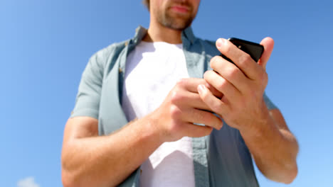 Vista-De-ángulo-Bajo-Del-Hombre-Usando-El-Teléfono-Móvil-En-La-Playa-En-Un-Día-Soleado-4k