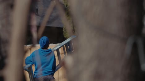 A-person-in-royal-blue-hoodie-and-hat-carries-a-ladder