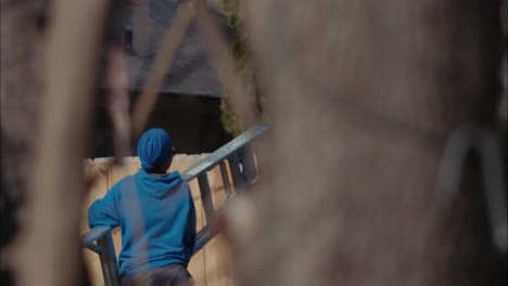 una persona con capucha y sombrero azul real lleva una escalera