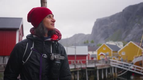 slow motion truck-up shot of a young female photographer tourist and her golden retriever dog photographing the beautiful fisher village of å and its red rorbu houses in the lofoten islands, norway