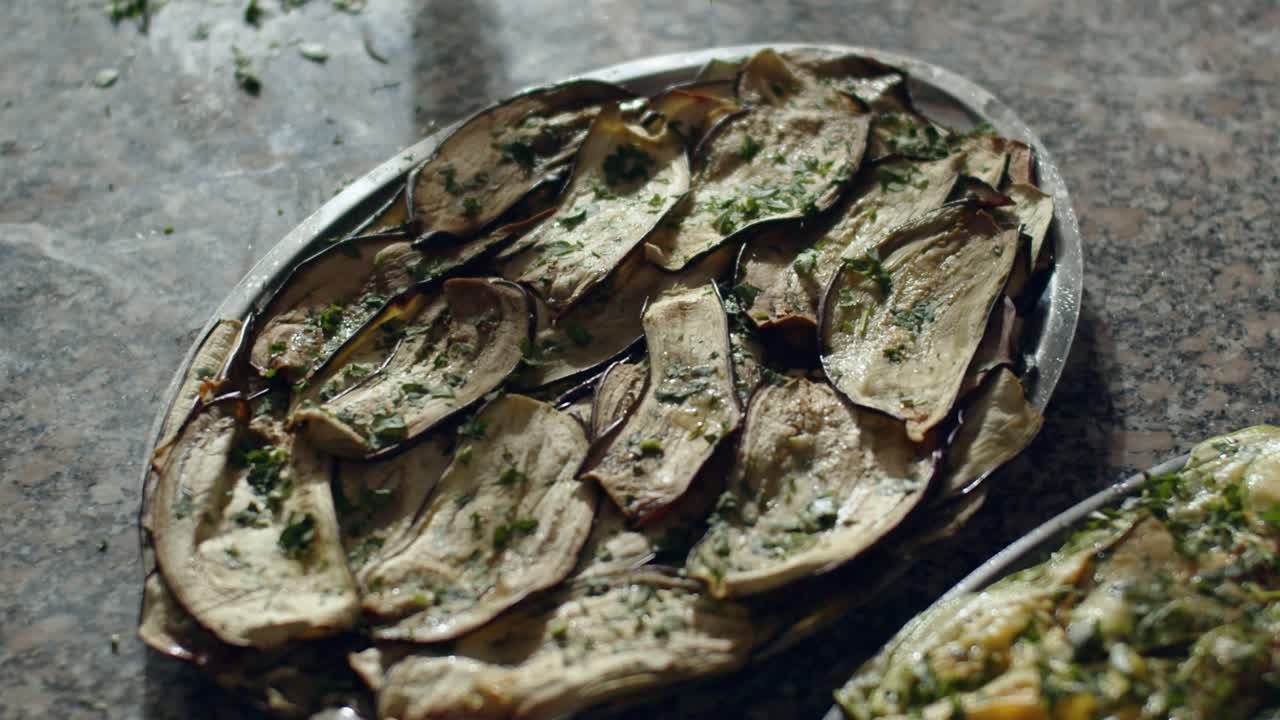 Pizza maker spreading parsley over pizza in kitchen