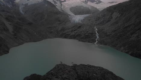 Aerial-view-of-the-Gauli-glacier-in-the-Bernese-Oberland-region-of-the-Swiss-Alps-with-a-panning-view-from-the-lake-towards-the-glacier-on-a-cloudy