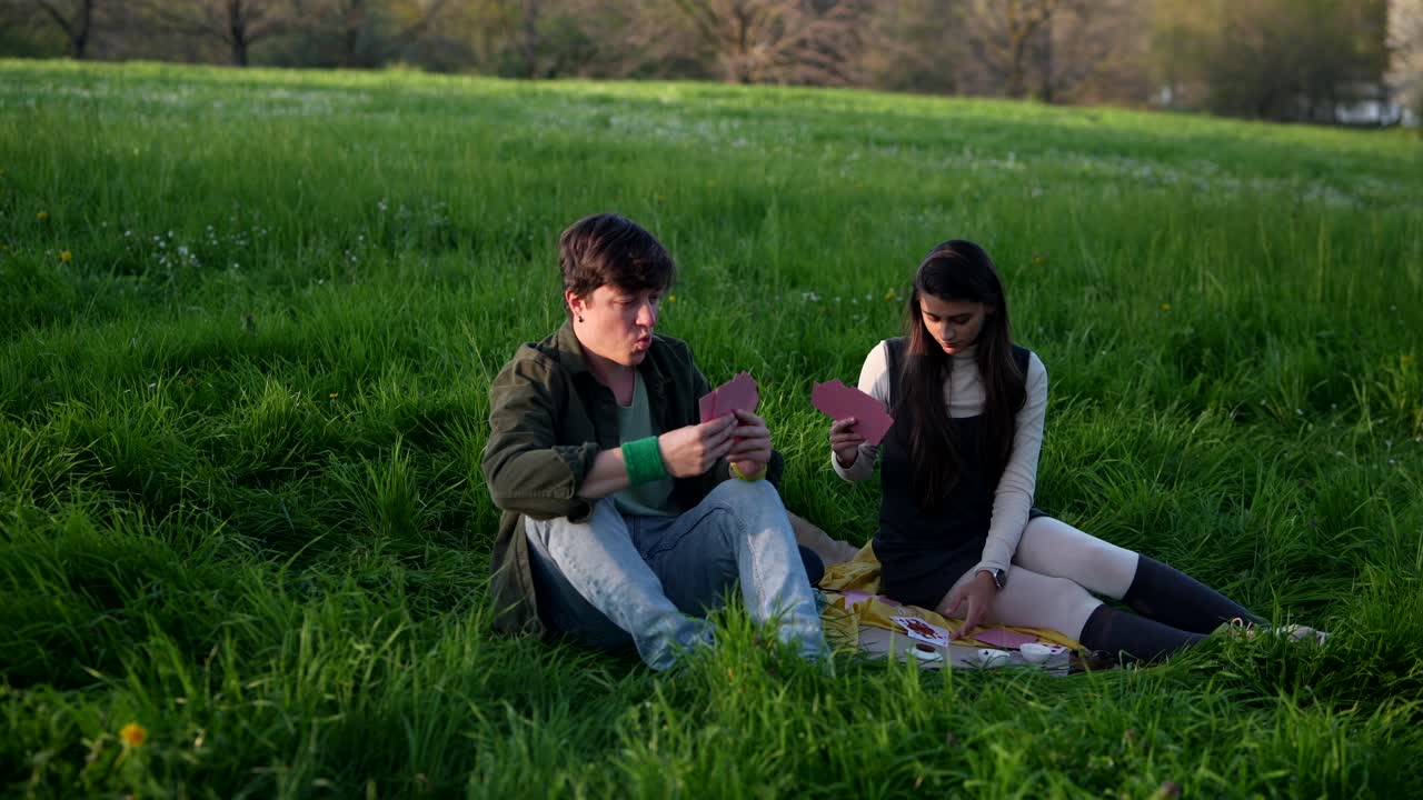 Couple Playing Cards at a Picnic in the Park