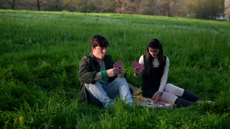 couple playing cards at a picnic in the park