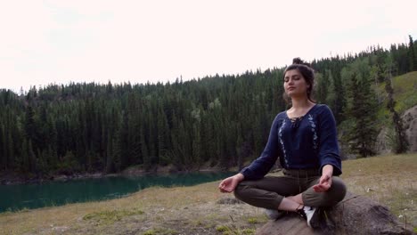 indian woman meditates on rock at miles canyon, medium shot