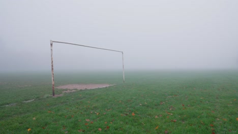 a rusty goalpost on a foggy football field during autumn