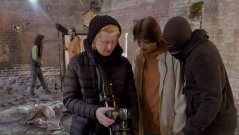 cameraman and actors reviewing a scene movie in a camera in a ruined building