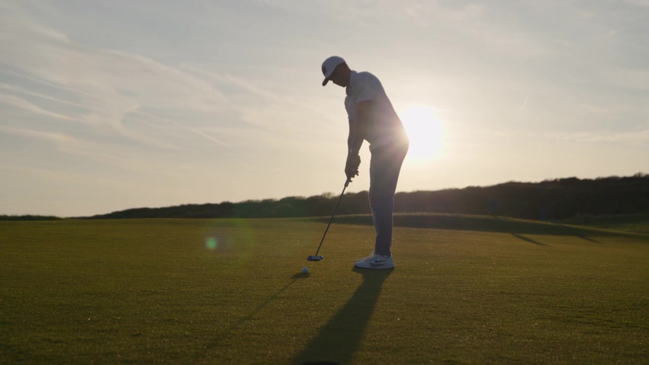 Golfer misses putt and looks disappointed, sunset golf course