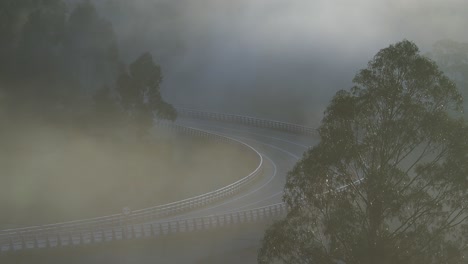 fog over a highway curve. one passing car