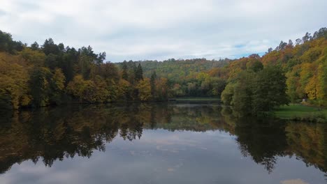 Die-Kamera-Bewegt-Sich-Knapp-über-Der-Oberfläche-Des-Teiches,-Der-Einen-Wunderschönen,-Farbenfrohen-Wald-Voller-Bäume-Umgibt