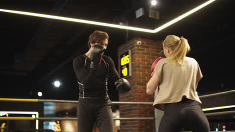 Pareja-De-Deportes-Activos-Peleando-En-El-Gimnasio.-Entrenador-Entrenando-A-Una-Chica-En-Forma-En-Un-Ring-De-Boxeo