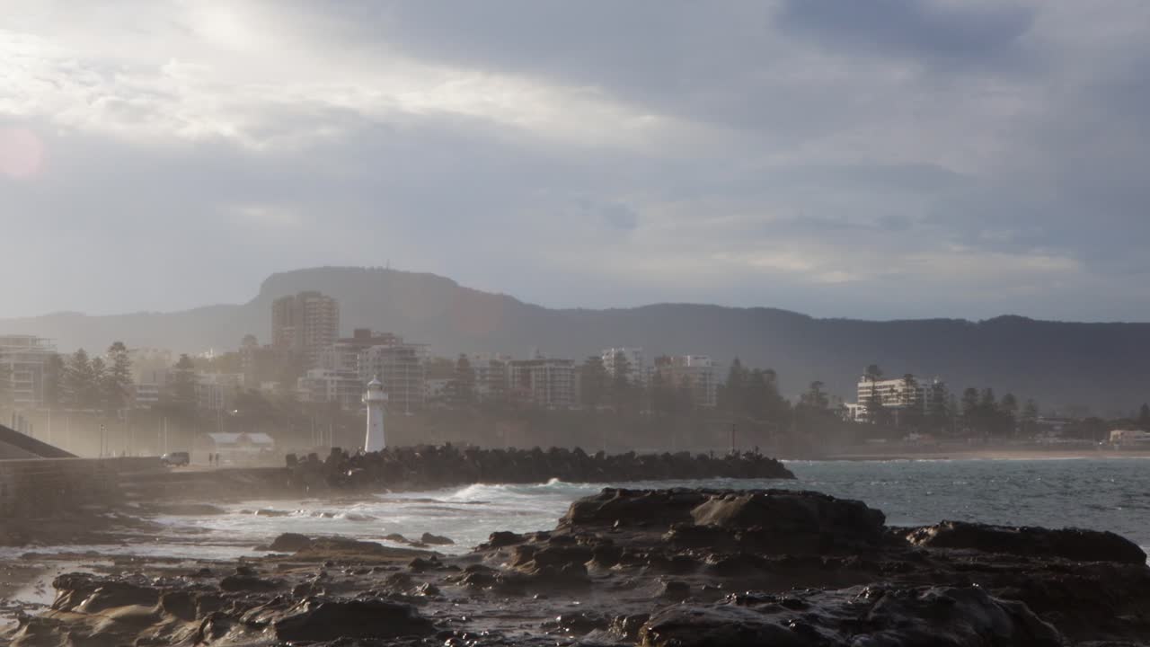 agua chocando contra la orilla rocosa del faro y la ciudad de wollongong nsw