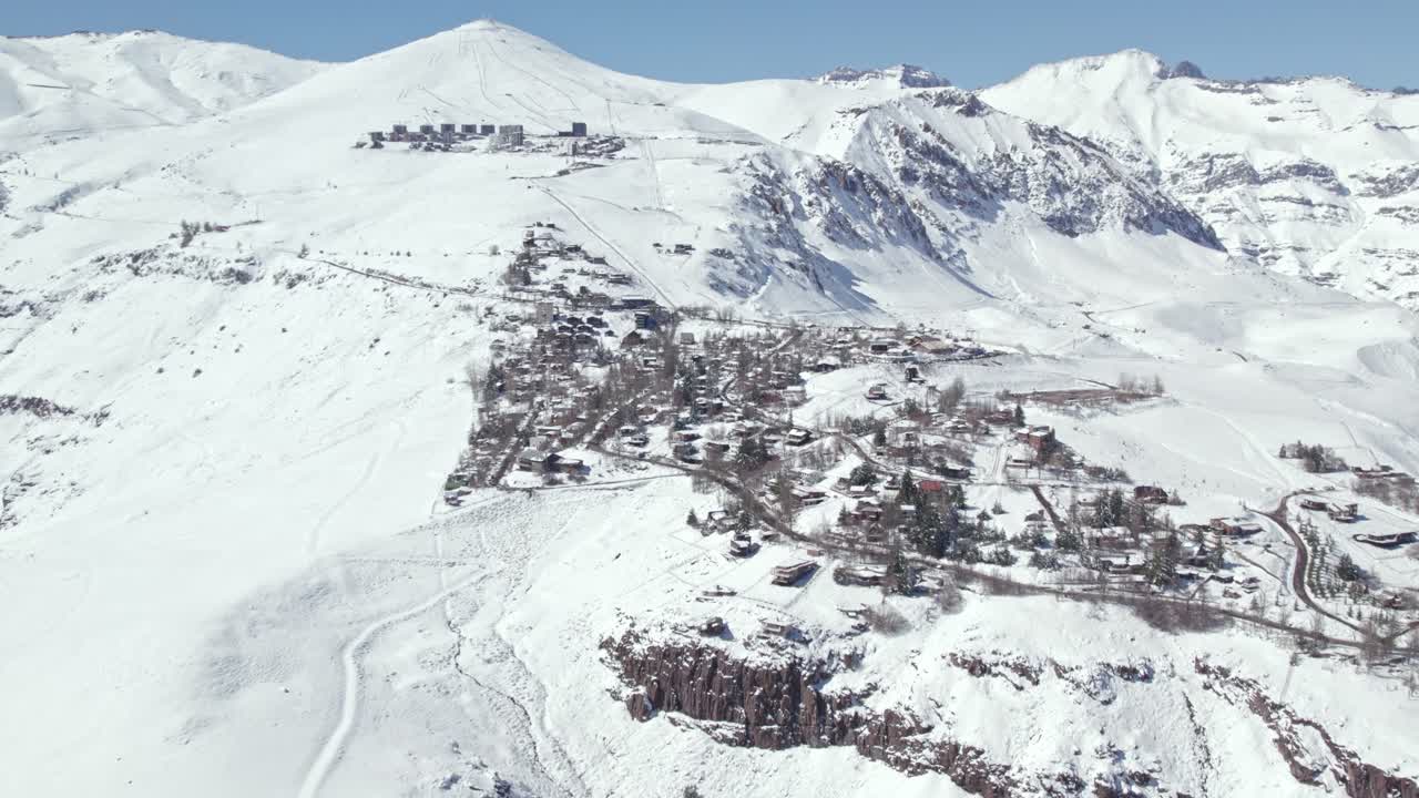 vista aérea panorámica rodeando el paisaje invernal de las montañas nevadas de farellones y un pintoresco pueblo en las montañas de los andes