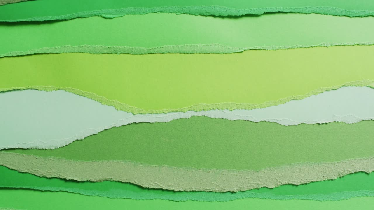 Video of close up of torn pieces of green paper background