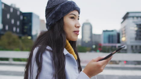 mujer asiática caminando y hablando en teléfono inteligente