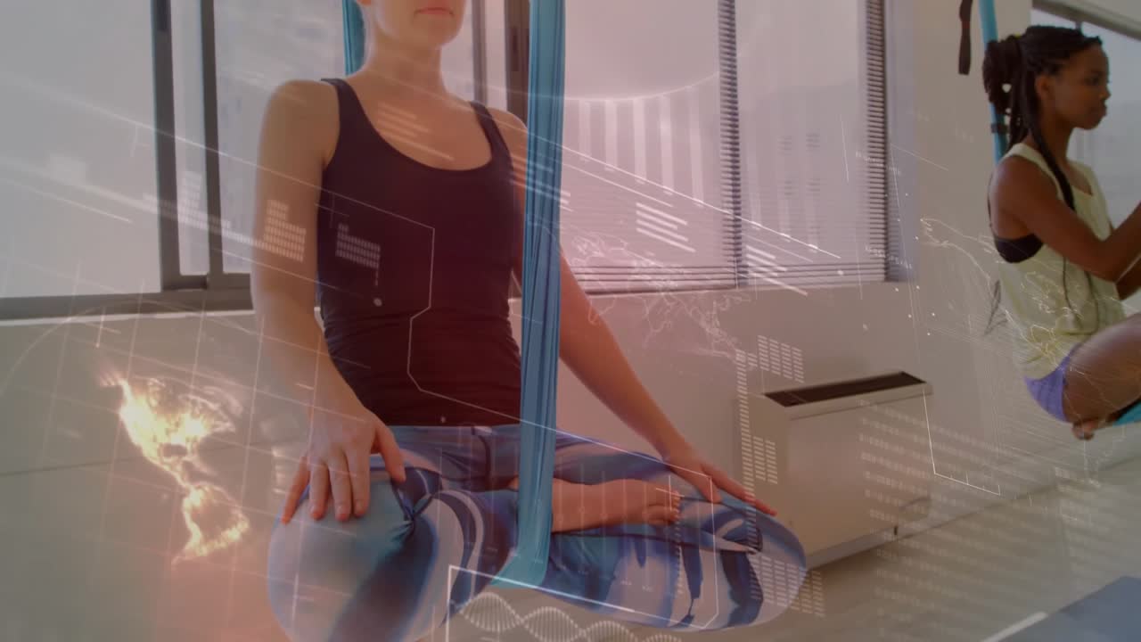 Dois praticantes de yoga segurando alças de tecido e elevando-se para a postura da flor de lótus aérea em um estúdio de fitness