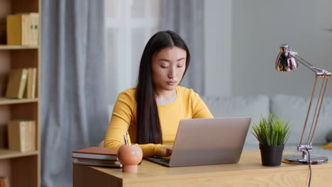 Woman working from home on laptop, stretching and relaxing at home.