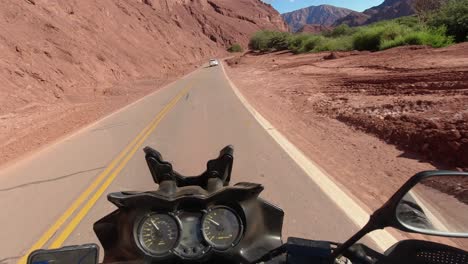 moto pov: motociclista sigue coche blanco en la carretera de la montaña de la roca roja