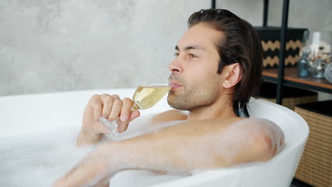 man relaxing in a bubble bath with champagne