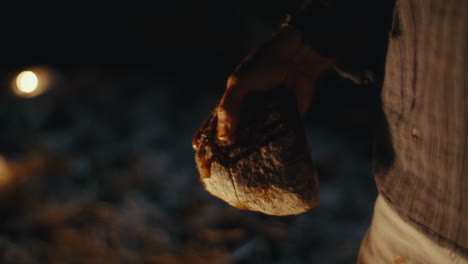 close-up of hand holding a stone dripping liquid in the dark