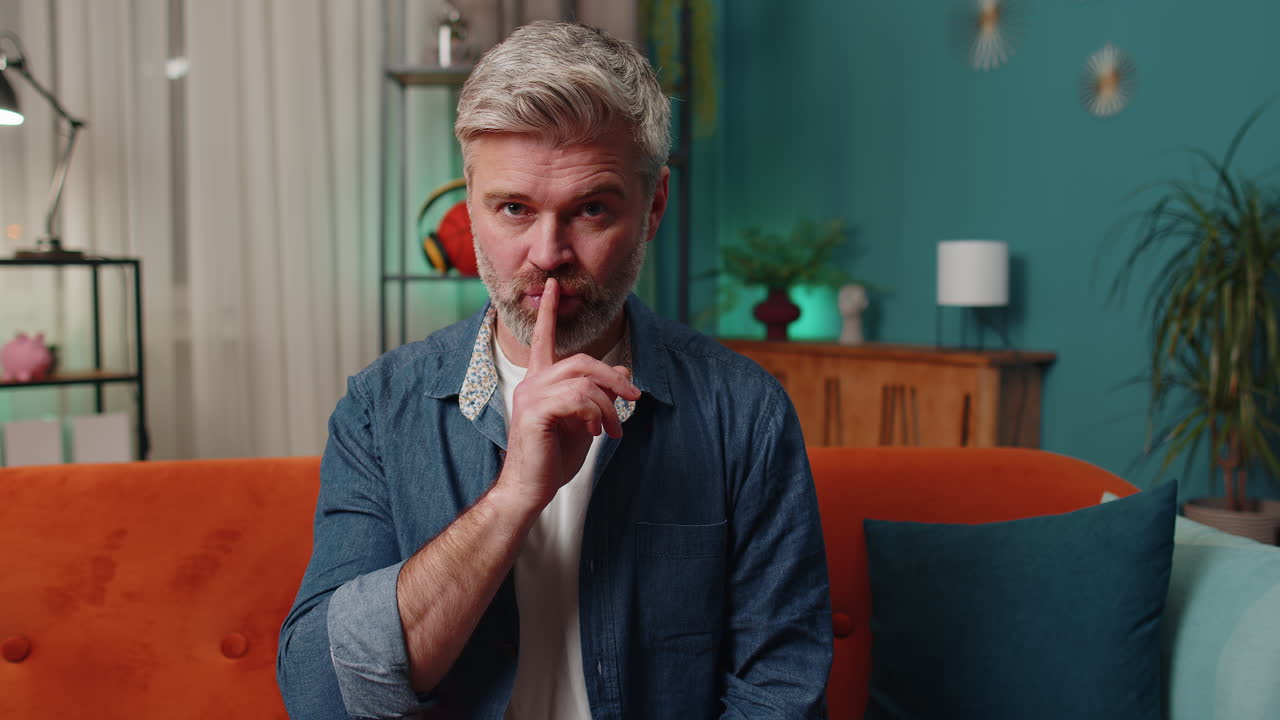 Man on Couch Gesturing Quiet and Stop