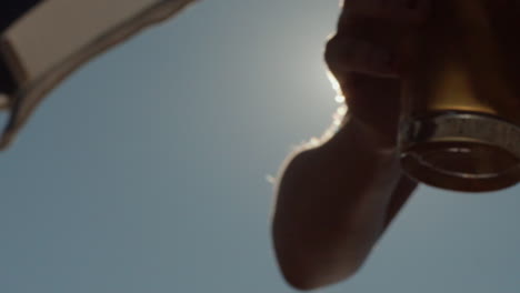 Close-up-of-drink-in-a-glass-under-umbrella-being-taken-with-hand,-Slowmo