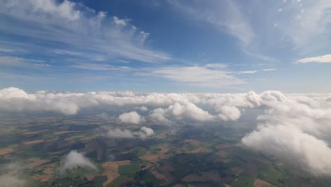 slow flying with an airplane trough the clouds and flat farm land of germany visible bellow