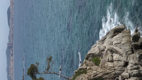 Rocky-coast-with-hiking-trail-rock-staircase-and-ocean-waves-splashing-vertical-format