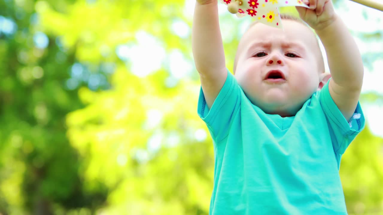 Süßer Babyjunge spielt mit einem Windrad.