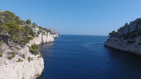 Drone-view-flying-over-the-mediterranean-sea,-getting-out-of-a-creek.-Sunny-day