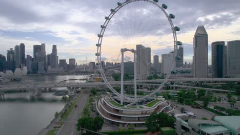 Video-Aéreo-Del-Horizonte-De-La-Ciudad-De-Singapur-Con-La-Noria-De-Observación-Del-Volante-De-Singapur,-El-Hotel-Marina-Bay-Sands-Y-Los-Jardines-Junto-A-La-Bahía-Al-Amanecer.