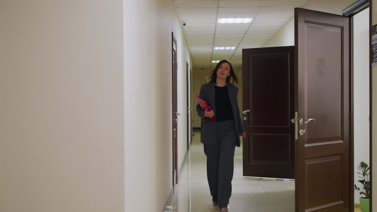 Businesswoman walking through office corridor holding documents in formal attire, approaching open office doors, professional environment, modern workplace, corporate life, and productivity