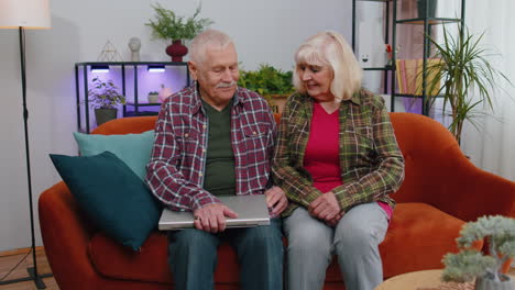 senior mature old man woman starts working on laptop, sends messages, makes online purchases at home