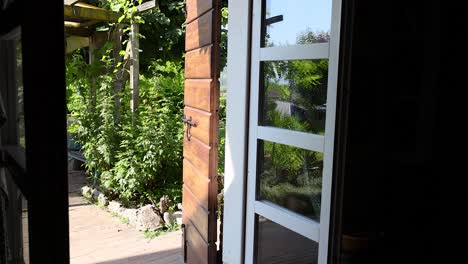 open door reveals lush garden and bench