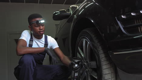 car mechanic cleaning car wheel