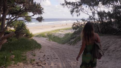 Mujer-Caucásica-Caminando-Cuesta-Abajo-En-La-Arena,-Da-La-Vuelta-Y-Hace-Un-Gesto-Para-Venir-A-La-Playa---Reserva-De-Cabecera-De-La-Playa-Principal-En-Point-Lookout,-Queensland,-Australia