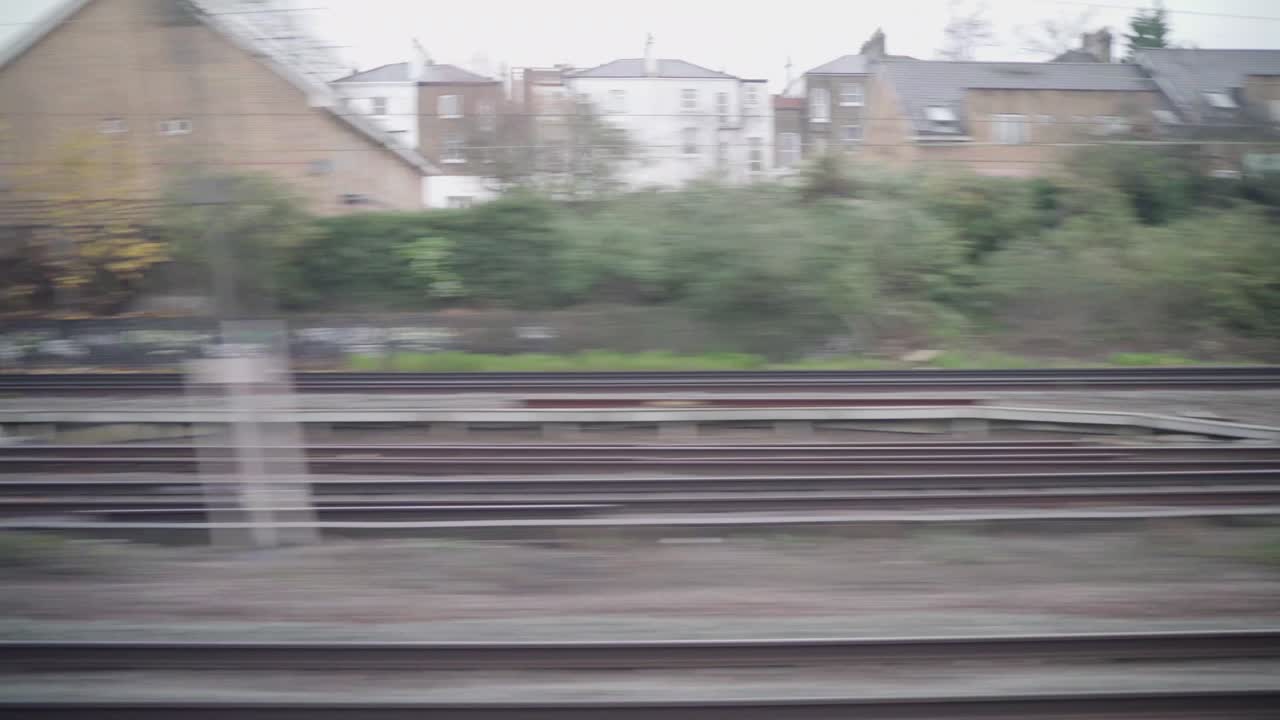 Window view of a train in london with a grey and cloudy weather and an ugly urban view.