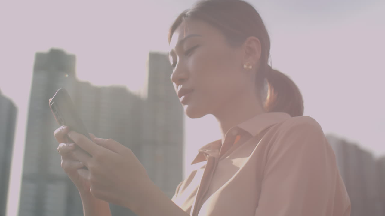 Asian Woman Using Mobile Phone in City