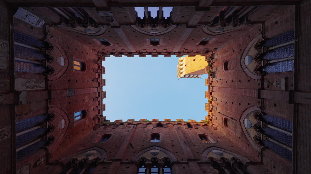 En levant les yeux depuis la cour, vue de la Tour du Mangia sous un ciel bleu clair