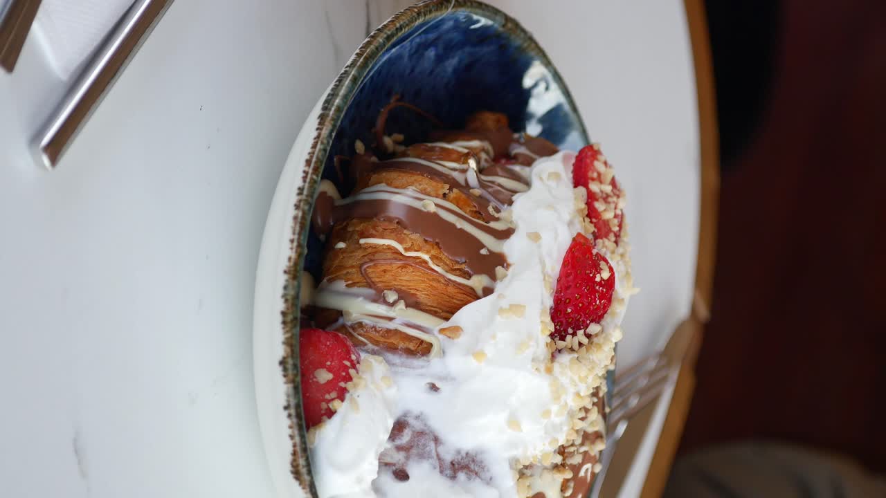 Croissant with chocolate, whipped cream, strawberries, and nuts