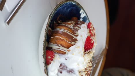 croissant with chocolate, whipped cream, strawberries, and nuts