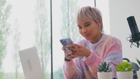 Vlogger-Femenina-Con-Micrófono-Transmitiendo-En-Vivo-Mirando-El-Teléfono-Móvil