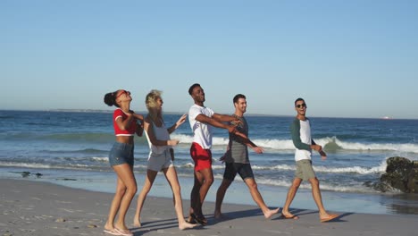 group of young adult friends walking on a beach talking 4k