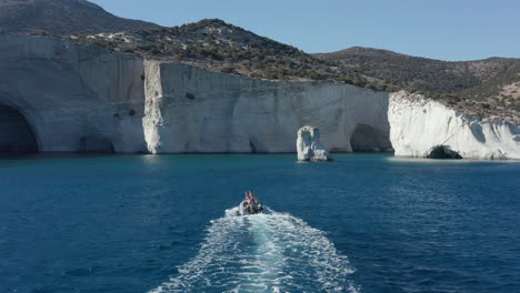 Aerial-Follow-Shot-of-Motorboat-on-Blue-Ocean-towards-White-Paradise-Cliffs