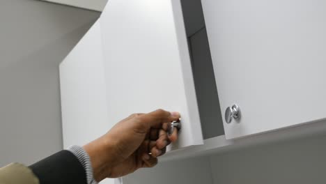 person opening a white cabinet