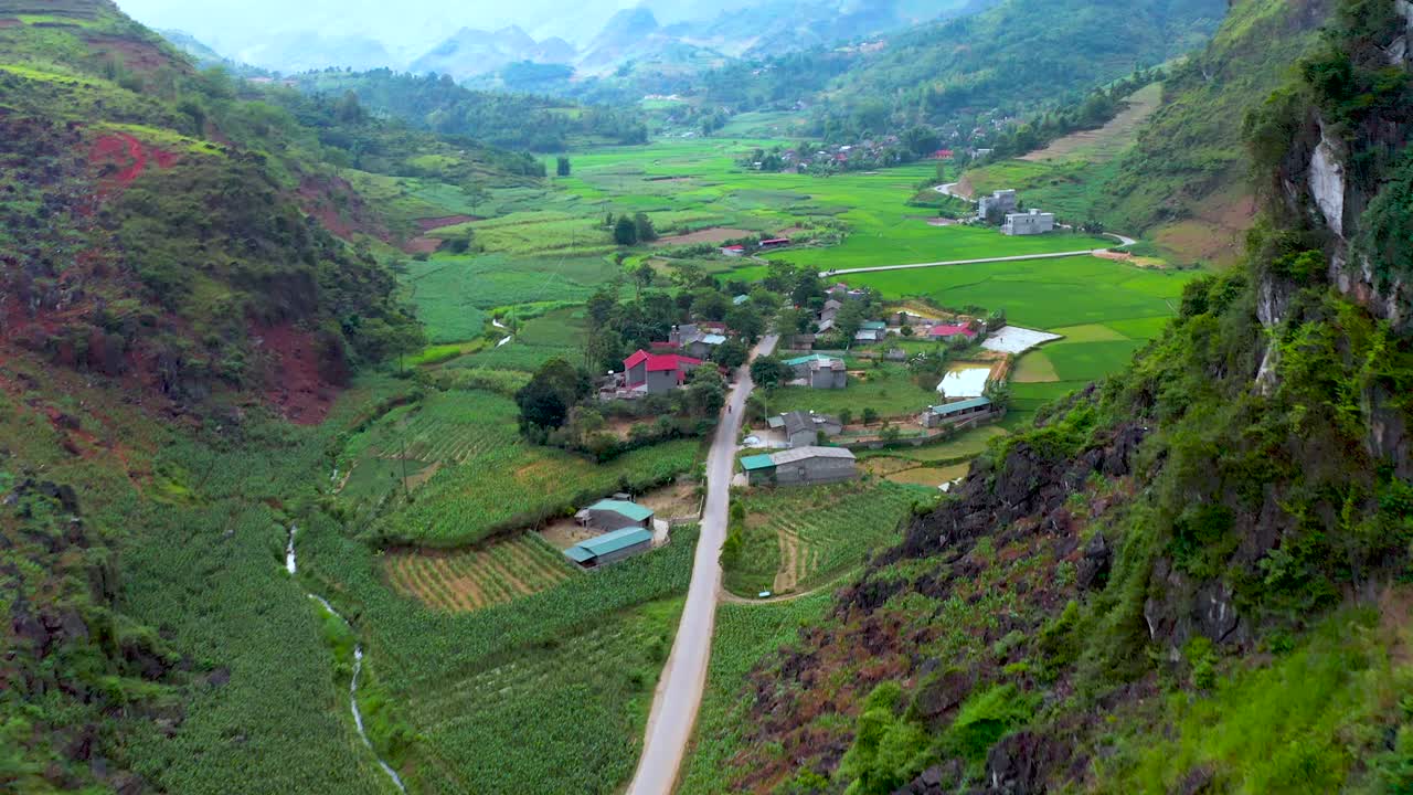 la carretera atraviesa una montaña para revelar tierras de cultivo ubicadas en un valle brumoso en el norte de vietnam