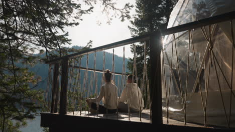 couple meditating on a deck overlooking a mountain lake